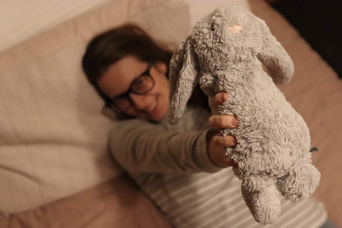 woman in gray sweater holding white bear plush toy