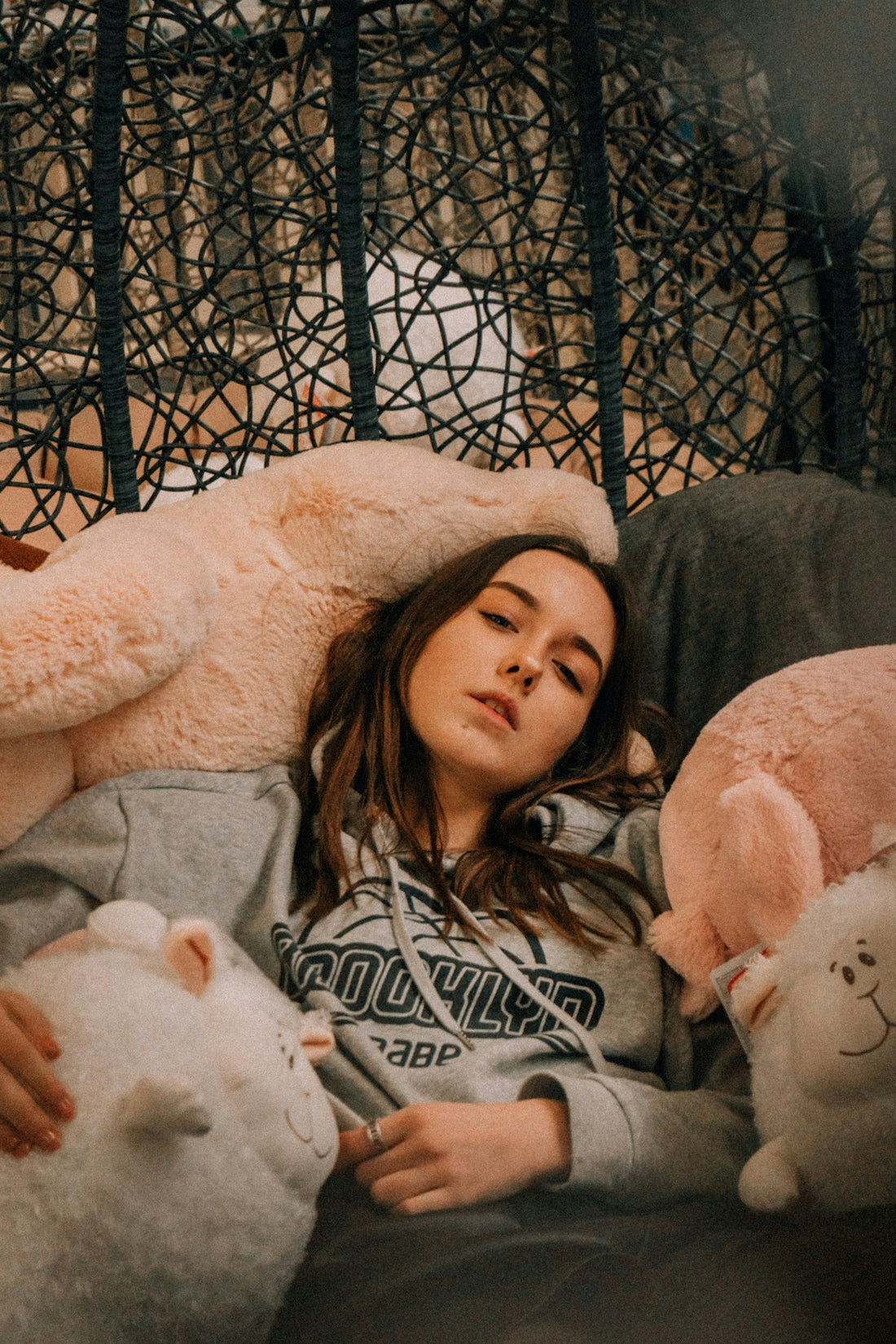 girl in white and black sweater sitting beside white bear plush toy