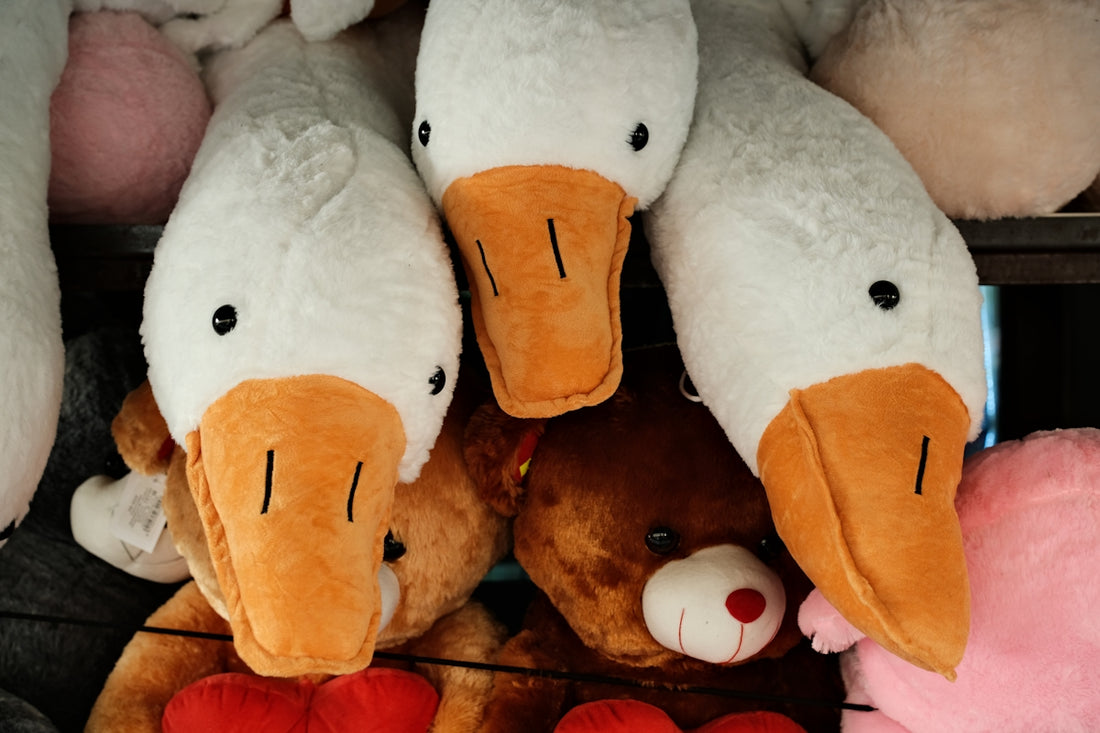 Three plush geese heads with teddy bears behind them