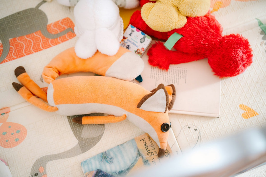 Plush fox toys and elmo on a patterned play mat